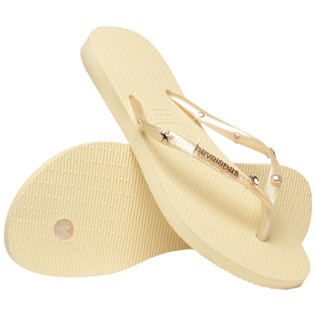 light yellow/buttercream sandals with yellow straps and crystals and pearls and star charms adorning the straps, one shoe leaning on the other toe side down