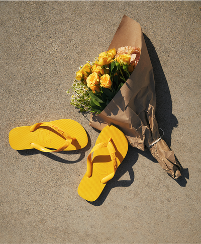two yellow top flip flops next to a yellow flower bouquet