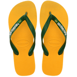 yellow flip flops with green straps, with a small brazil flag and havaianas written in white on the strap, top view