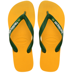 yellow flip flops with green straps, with a small brazil flag and havaianas written in white on the strap, top view