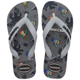 Pair of kids' Havaianas Minecraft flip-flops with white straps and a gray printed footbed. The design features Steve and Alex, the Ender Dragon, pixelated tools, gems, hearts, and Minecraft branding. The Havaianas logo appears on the straps and near the heel of each sandal.
