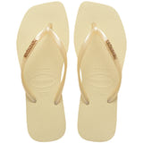 Pair of buttercream flip flops with a brand logo on a white background