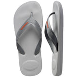 Pair of grey flip flops with orange Havaianas logo, with left shoe in focus on a white background