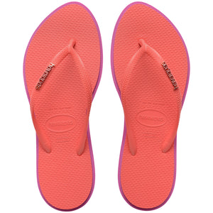 Pair of pink Havaianas flip flops with a  logo on the sole against a white background