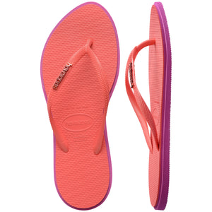Pair of pink Havaianas flip flops with a  logo on the sole against a white background, with left shoe in focus