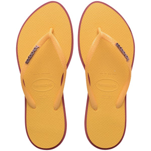 Pair of yellow Havaianas flip flops with red accents on a white background