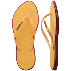 Pair of yellow Havaianas flip flops with red accents on a white background, with left shoe in focus