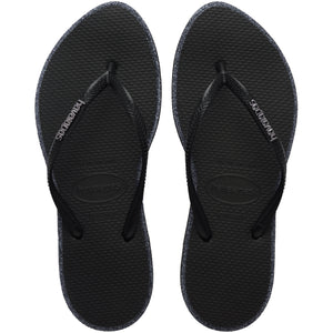 Pair of black Havaianas flip flop with glitter accent and black logo on the strap on a transparent background
