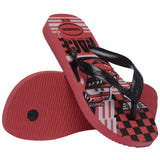 Kids' Havaianas Disney Cars flip-flop shown from an angled top and bottom view. The sandal features black textured straps, a red sole, and a graphic footbed with Lightning McQueen artwork and racing-inspired patterns. The red rubber outsole has a textured tread for added grip.