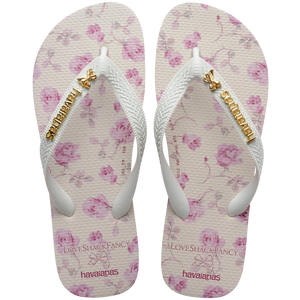 women's havaianas x loveshackfancy flip flops, footbed with white background and pink roses, white straps with a gold bow and gold havaianas charm, top view
