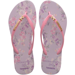 women's loveshackfancy x havaianas flip flops with a purple and pink floral footbed, pink straps, and a gold bow charm and gold havaianas logo on the strap, top view