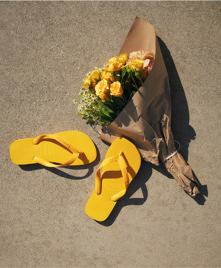 two yellow top flip flops next to a yellow flower bouquet