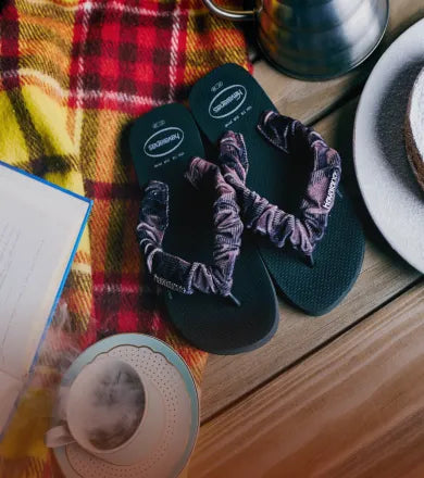 Pair of Havaianas flip flops with fluffy fabric straps on a Fall themed table.